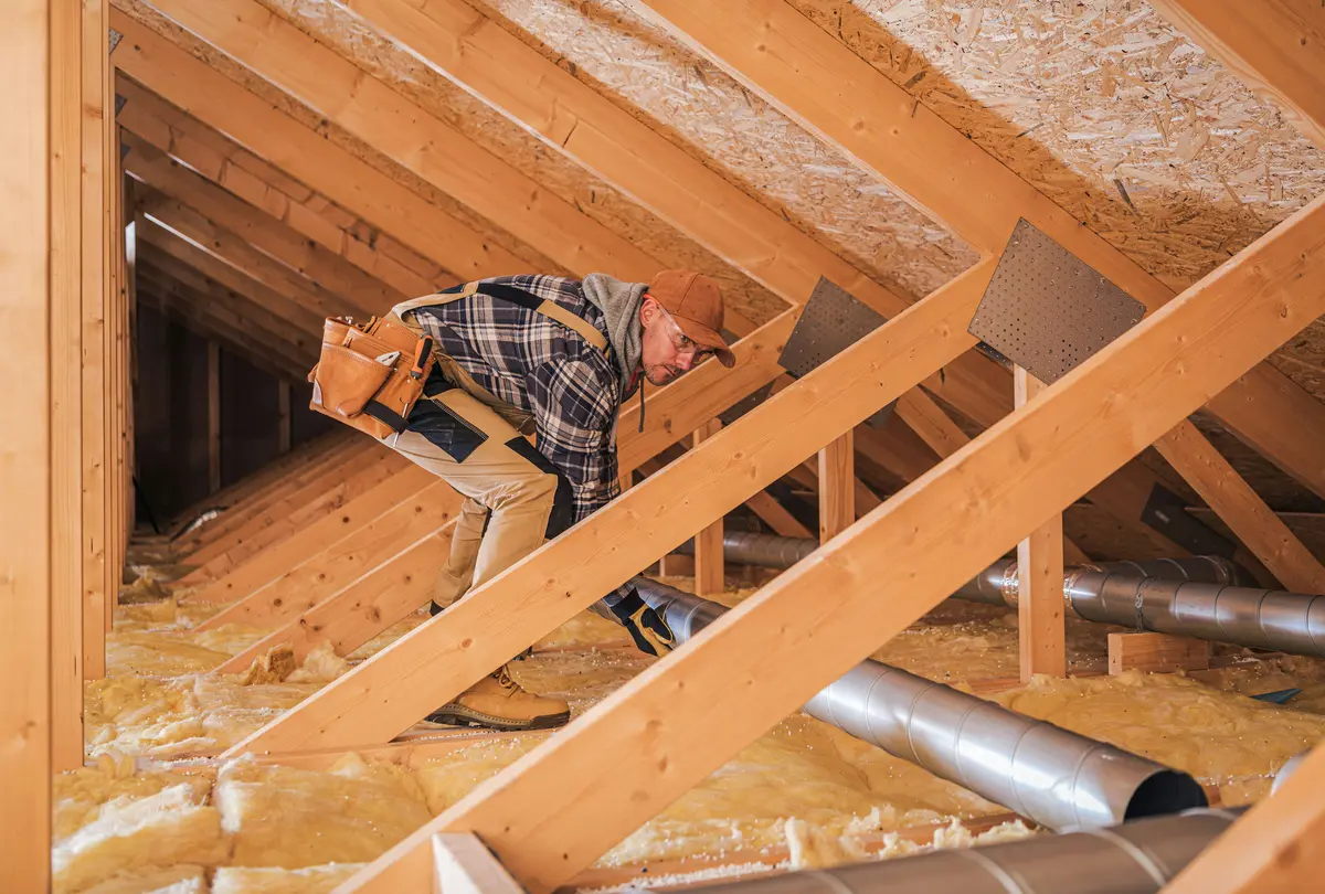 HVAC technician installing ductwork in an attic space